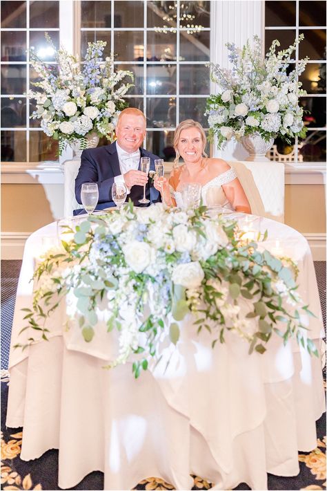 bride and groom sit at sweetheart table with white and blue floral details | Elegant costal Bonnet Island Estate Wedding with shades of blue details photographed by LBI wedding photographer Idalia Photography. Blue Hydrangea Sweetheart Table, Sweetheart Table Hydrangea, Sweetheart Table Wedding Blue, Blue And White Sweetheart Table, Dusty Blue Sweetheart Table, Head Table Wedding Flowers, Sweetheart Table Florals, Square Wedding Tables, Barker Wedding