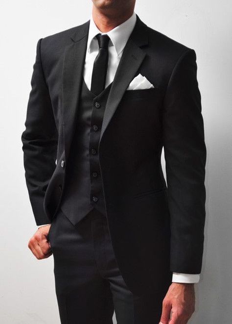 A tuxedo, often referred to as a "tux" in informal contexts, is a formal evening suit distinguished primarily by satin or grosgrain facings on the jacket's lapels and buttons, and a similar stripe along the outseam of the trousers. Traditionally black or midnight blue, the tuxedo is worn with a formal shirt, a bow tie, and patent leather shoes. It is the standard attire for events described as black-tie and is frequently chosen for elegant events, weddings, and sophisticated soirées. Black Suit Men Casual, Casual Black Suit, Suit Men Casual, Tailored Wedding Suit, Groom Attire Black, Wedding Suits Men Black, Groom Suit Black, Wedding Tux, Black Suit Men