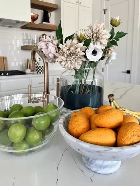 Kitchen hosting essentials with a marble fruit bowl, marble cake stand, plastic clear serving bowl, dipped vase for faux florals and other kitchen decor. #LTKSeasonal #LTKstyletip #LTKhome Modern Fruit Bowl Display, Styling Kitchen Counters, Fruit Basket Ideas, Modern Fruit Bowl, Peninsula Kitchen, Small Kitchen Island Ideas, Fruit Bowl Display, Marble Cake Stand, Tiered Fruit Basket