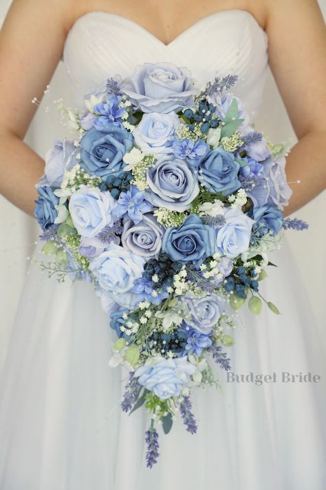 This lovely assortment of lavender, lilac, steel blue and periwinkle is bound to turn heads on your wedding day. This lovely cascading brides’ bouquet from the is an absolutely breathtaking arrangement for any bride to be, in any season. Lavender fronds and babies breath complete the look and add a delicate realism to this beautiful bouquet. This bouquet is 10” wide, 18” long, and is crafted by our in-house florists without using a foam base to anchor the flowers to the bouquet. Instead, we wire Waterfall Bouquet Wedding Blue, Light Blue Bridesmaids Bouquets, Bridal Bouquet Forget Me Nots, Blue Winter Wonderland Wedding, Flower For Wedding Bouquet, Periwinkle Themed Wedding, Mint Blue Wedding Theme, Bridgerton Blue Wedding, Dark And Light Blue Wedding