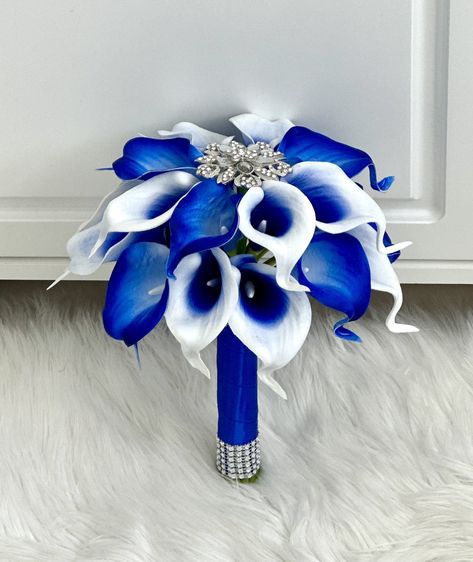 "💐 18-20 lily Picasso royal blue calla lily brooch bouquet! Choose your ribbon color.  💐 1 calla lily bridesmaid bouquet with a center brooch. The handle contains bling at the top and bottom.  Price Guide: 💐brooch bridal bouquet- $195      Bridal bouquet (10\") $110      10 lily bridesmaid bouquets - $38 each      18-20 (8\") lily bridesmaid bouquet- $65      6 lily bridesmaid bouquet- $30      4 Lily toss brooch bouquet- $25      groomsmen bouts - $7 each      wrist corsage - $25 each      g Blue Lily Bouquet, Bridesmaid Bouquet Blue, Blue Calla Lily Bouquet, Blue Bridesmaid Bouquet, Calla Lily Bridesmaid Bouquet, Blue Calla Lily, Prom Flowers Bouquet, Lily Bouquets, Blue Lilies