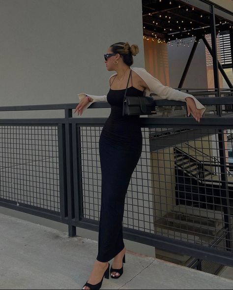 A girl is leaning against a railing with a long black, skin tight dress on. She’s  wearing black heels, a beige shrug, and a little black purse. Body Con Maxi Dress Outfit, Brunch Date Outfit Summer, Heels Baddie, Maxi Body Con Dress, Black Bodycon Dress Outfit, Long Black Dress Outfit, Long Black Bodycon Dress, Tight Maxi Dress, Black Maxi Dress Outfit