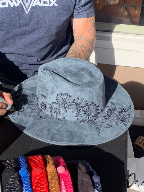 Floral art burned on a blue suede fedora hat.  This hat can be sold as is or it also has room to add customization. Designs are freehand so every hat is one-of-a-kind and subject to artist interpretation. Prices vary by design and detail.  Once we receive your order we will send you a price for additional artwork (if any) and begin artwork upon receipt of payment.   Due to the nature of customization and sanitation, this product is non-refundable.  This item is ready to ship, as is. Turn around time for additional customization will be adjusted and communicated according to how many orders are waiting. Burned Fedora Hat Designs, How To Make A Hat Band, Burn Hats, Burnt Hats, Burned Hats, Hand Burn, Felt Cowboy Hats, Felt Hats, Painted Hats