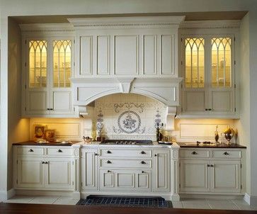 . The Gothic-inspired insets in the glass door would get lost if placed on top of a wood door. By placing a light inside these display cabinets, we can see the strong patterns of the filigree work. White Kitchen Interior Design, White Kitchen Interior, Beautiful White Kitchens, Old World Kitchens, Victorian Kitchen, French Country Kitchens, Interior Vintage, Kitchen Hoods, French Country Kitchen