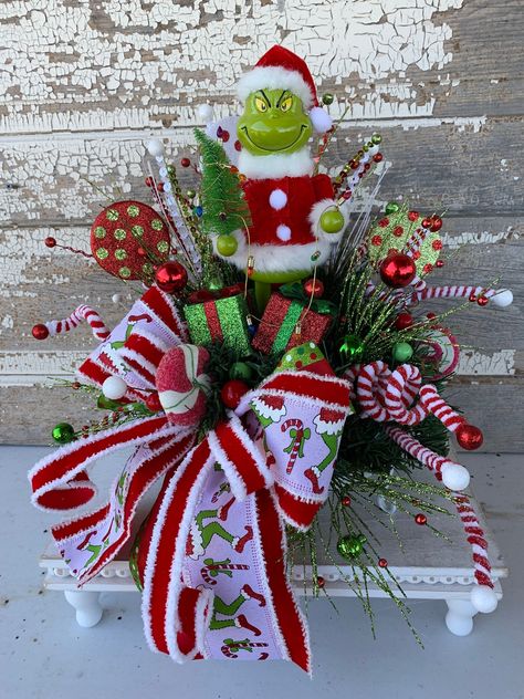 Christmas Centerpiece Christmas table centerpiece Christmas floral arrangement table decor Santa Elf This Christmas arrangement will look great as a centerpiece for your table or anywhere you want to add Christmas cheer. The arrangement is on a metal white tray with greenery, sprays, ball picks, candy picks, adorable Santa holding a tree with garland of lights and a holiday bow.  Measures approx. 16"H X 12"W SHIPPING FEE IS INCLUDED IN LISTING PRICE  Please check out my other listings and Thank you for looking! Please follow me on Pinterest" for all of my latest and past designs  Link: https://www.pinterest.com/cylesdazzlingdesigns/boards/ Please follow me on Facebook "CylesDazzlingDesigns" for all of my latest designs and/or Custom order your design. Link: https://www.facebook.com/cylesda Grinch Arrangement, Xmas Centerpiece Ideas, Grinch Centerpiece, Tree With Garland, Grinch Diy, Centerpiece Christmas Table, Candlestick Arrangements, Table Centerpiece Christmas, Christmas Centerpieces Cheap