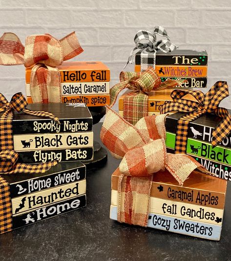 These fun book stacks will look beautiful with your holiday decor.  Made from wood and painted to look like books there is a festive ribbon tied around them and vinyl lettering on each book.  They are sealed with a poly coat sealant. Please choose your style from the drop down menu. Each book stack is approximately 5" x 3.5" x 2.25" Black pedestal in listings is not for sale.  You will receive book stack only. Each stack will come cellophane wrapped and is ready to ship. If you have any questions, please message me. Fall Craft Sale Ideas, Fall Stacked Books Diy, Fall Book Stack Diy, Fall Diy Crafts To Sell, Diy Wood Books, Wood Books, Halloween Tiered Tray Decor, Block Signs, Stacked Books