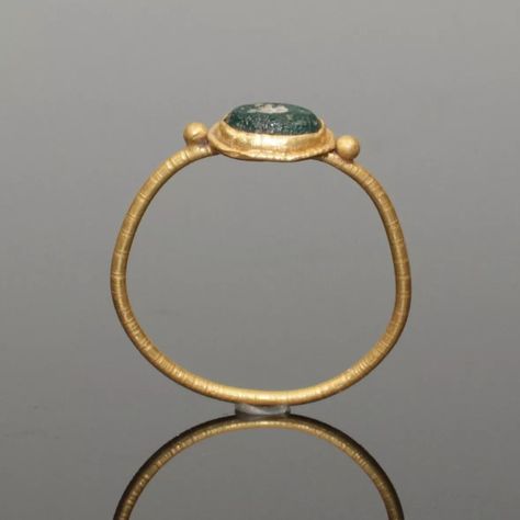 LOVELY ANCIENT ROMAN GOLD RING. ANCIENT ROMAN GOLD RING. DATES: CIRCA 2nd CENTURY AD. SUPPORTING A CENTRAL OVAL BEZEL SET WITH AN IRIDESCENT GREEN GLASS STONE. HAVING A SOLID BAND..#jewelrylover #handcraftedjewelry #jewelryinspiration #jewelrydesign #jewelryobsessed #jewelryoftheday #jewelrygoals #jewelryfashion #jewelrytrends Sun Outfits, Ancient Gold Ring, Black Nativity, Storm Comic, Ancient Rings, Lost Wax Jewelry, Etruscan Jewelry, Medieval Ring, Ancient Roman Jewelry