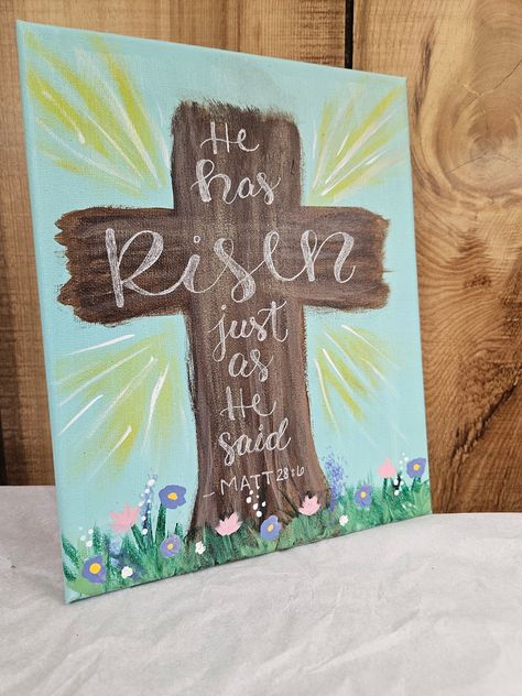 "Decorate for easter with this beautiful reminder of the resurrection! A floral outside scene of the cross with \"He has Risen just as he said - Matt. 28:6\" is handlettered in white ink.  There are two size options: #1 Dimensions: H: 10 in W: 10 in #2 Dimensions: H: 10 in W: 8 in" Easter Cross Paintings On Canvas, Easter Ideas For Kids Crafts, Easter Paintings On Canvas Jesus, Easy Easter Painting Ideas, Easter Cross Decor, Horse Canvas Painting Easy, Bible Painting Ideas On Canvas, Easy Easter Paintings On Canvas, Cute Easter Paintings