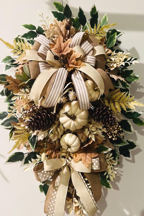 PURCHASE: 30-inch Taupe Faux Pine Everyday Fall  Wreath! Click the ADD TO CART button on the right and follow the prompts. A shipping notification will be emailed to you as soon as it is shipped. DESCRIPTION: Taupe 30-inch Faux Pine Wreath Base; Cream Pumkins, Pine Cones/Fall Bush  Cream/Tan Fall Leaves; Beautiful Triple Layered Bows and Ribbon Tails; Greenery: Rosemary Picks, Lambs Ear, Cream Floral Stems, etc. Green with white tips Ficus Stems Deco Mesh Curls Dimensions: Tip to Tip; 37 L, 23 W Table Fall Decor, Farmhouse Swag, Elegant Fall Wreaths, Front Door Decorations, Front Door Swag, Fall Swags, White Tips, Swag Wreath, Wreath Base