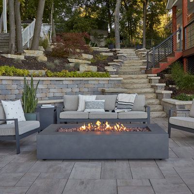 The Fire Pit table is a welcome addition to most outdoor living spaces. Adding warmth and a relaxing ambiance for any occasion. This product comes complete with a steel lid for increased functionality, red lava rock, and a polyester protective cover, and can be converted to Natural gas by a Certified Gas Technician with the conversion kit that is included with the table. Enhance the look of your table with optional accessories like a propane tank cover, gas hose cover, and real flame fire glass. Real Flame Size: 14.5" H x 69.75" W x 31.75" D, Finish: Weathered Slate Real Flame AEGEAN Propane/Natural Gas Outdoor Fire Pit Table in Weathered Slate | Size 14.5" H x 69.75" W x 31.75" D | AllModern Ground Level Deck With Fire Pit, Rectangular Fire Pit Ideas, Rectangular Fountain, Fire Tables Outdoor, Rectangular Gas Fire Pit, Rectangle Fire Pit, Outdoor Fire Table, Natural Gas Fire Pit, Outdoor Fire Pit Table