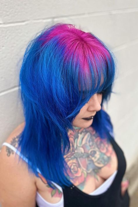 Witness the striking combination of bright pink roots and blue hair with bangs on the right side of this person's head! 💖💙 Embrace your adventurous side and make a statement with this eye-catching hairstyle. Ready to stand out from the crowd? Book your appointment now and let's create your own unique look! #BrightPinkRoots #BlueBangs #ColorfulHair #HairInspiration #BookNow #HairMagic Roots Different Color Hair, Unique Vivid Hair Color, Hair Dye Ideas Bright, Blue Hair Pink Bangs, Blue Hair With Pink Tips, Pink And Blue Hair Dye Ideas, Blue Hair Pink Tips, Purple Roots Blue Hair, Pink And Blue Short Hair