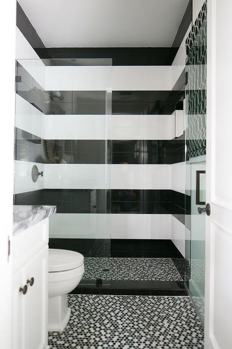 Black and white striped shower surround tiles are fitted with an oil rubbed bronze shower kit fixed behind a glass partition and beautifully complemented with black and white mosaic shower floor tiles which continue out into the bathroom to frame a white washstand. Toilet Tiles Design, Black Tile Bathrooms, White Tile Shower, Black White Bathrooms, Bathroom Showers, Bathroom White, White Bathroom Tiles, Bathroom Floors, Shower Floor Tile