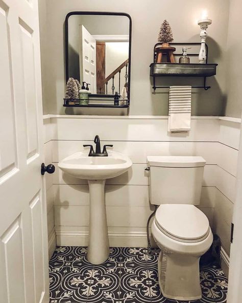 This farmhouse half bath with a white shiplap half wall features a white pedestal sink with black faucet. The sink stands on black and white mosaic floor tiles under a black frame mirror with shelf. Half Bathroom Ideas With Pedestal Sink, Half Bath With Pedestal Sink, Pedestal Sink Bathroom Ideas, Farmhouse Half Bath, White Hexagon Tile Bathroom, Bathroom With Pedestal Sink, Modern Half Bath, Half Bath Decor, Pedestal Sink Bathroom