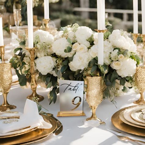 gold mirror table numbers for wedding on a white table white flowers and gold plates Elegant White And Gold Wedding Decor, Classy Wedding Flower Arrangements, Tall Flowers Wedding Table, Brass Wedding Table Decor, Classy Wedding Ideas Decor, Elegant Classy Wedding Decor, Glamour Wedding Decorations, Romantic Vintage Wedding Decorations, Classy Wedding Table Decor