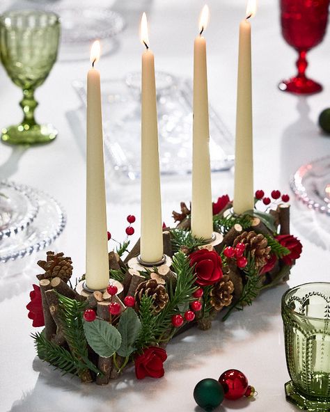 Just the thing to add a touch of luxury to your dining room this festive season, our long candle holder is lovingly crafted from mini yule logs with a natural bark finish for a rustic Christmas decoration that’s sure to create an impressive feature. The carefully interwoven logs feature evergreen leaves and pine sprigs, as well as real foraged pine cones for a traditional look. Completing the classically festive colour palette, shiny red holly berries and delicately curled wooden roses are nestl Wooden Yule Log, Long Candle Holder, Yule Logs, Long Candle, Yule Crafts, Christmas Roses, Christmas Candle Holder, Log Candles, Long Candles