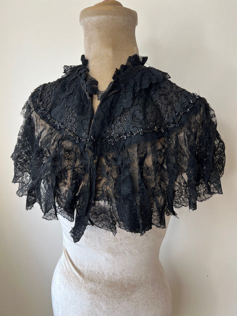 Victorian lace mourning cape, Victorian capelet, jet bead cape. One Size A beautiful, delicate Antique Victorian black lace cape with black jet beads.  It needs some TLC, there are some tears in the lace that need repairing and the top hook and eye is missing at the neck.   One Size. Please check measurements: Neck circumference 35cm Length - 31cm Width across arms and chest (flat) - 60cm Victorian Capelet, Capelet Crochet, Victorian Cape, Lace Trend, Crochet Capelet, Beaded Cape, Costume Capes, Vampire Clothes, Lace Cape