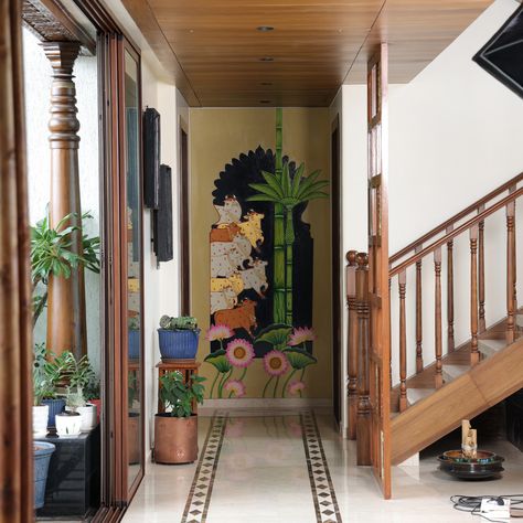 The endearing Pichwai mural, with its intricate detailing in the cows and rich colors, reflects devotion and tradition. The mesmerising Shrinathji Pichwai painting showcases the elegance of this beloved Indian art, while the Gond Painting at the end of a corridor captures the essence of tribal life with bold lines and vibrant shades. Indian Wall Murals Home Interiors, Indian Mural Wall Art, Pichwai Paintings Cows, Pichwai Art Paintings, Pichwai Cow Painting, Indian Wall Painting, Indigenous Crafts, Pichwai Painting, Gond Painting