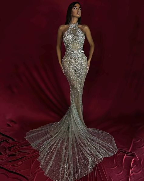 To purchase this stunning gown, send us a DM at @reineecouture. This show-stopping, form-fitting gown is the epitome of red carpet glamour. Featuring a high halter neckline, the gown is encrusted with shimmering crystals that catch the light from every angle, creating a dazzling, head-turning effect. The crystal embellishments are intricately placed to enhance the body’s natural curves, while the sheer mesh fabric adds a sultry touch of sophistication. The fitted silhouette hugs the figure ... High Neck Gown, Nude Gown, Silver Gown, Gold Gown, Fishtail Skirt, Embellished Gown, Stunning Gowns, Beaded Gown, Mermaid Silhouette