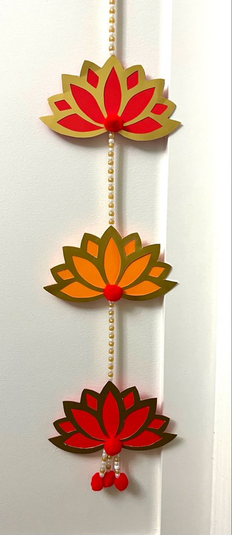 Paper crafted wall hanging with traditional lotus cutouts. Diy Lotus Wall Hanging, Arangetram Decor, Lotus Cutout, Holi Ideas, Lotus Wall Hanging, Diwali Card Making, Traditional Wall Hanging, Lotus Decor, Ganpati Decor