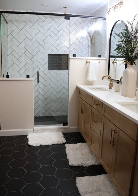 This beautiful bathroom features hexagon floor tiles with coordinating hexagon mosaic in the shower inset. The dark tiles are nicely juxtaposed against the white subway tiles in a herringbone pattern. Subway Tile Bathroom Dark Floor, Black Hexagon Flooring Bathroom, Bathroom Dark Hexagon Tile Floor, Bathroom Remodel Hexagon Tile Floor, Bathroom With Black Hexagon Floor Tile, Dark Hexagon Tile Bathroom, Shower With Black Floor, Black Octagon Tile Bathroom, Bathroom Black Tile Floor