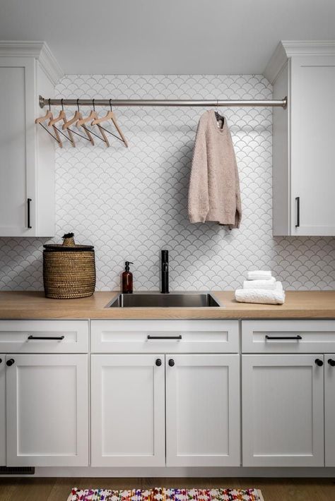 Stylish laundry room design with white cabinetry, wood countertop, modern backsplash tile, and hanging rod for drying clothes. A perfect combination of functionality and contemporary style.Laundry room with white cabinets, wood countertop, backsplash tile, and drying rod.#LaundryRoomDesign #HomeOrganization #InteriorDesign #HomeRenovation #ClarkAndAldinePin Light Gray Laundry Room Cabinets, Laundry Room Ideas White Cabinets, Butcher Block In Laundry Room, Laundry Room Tile Backsplash, Tile In Laundry Room, Laundry Room With White Cabinets, Laundry Room White Cabinets, Butcher Block Laundry Room, Laundry Backsplash