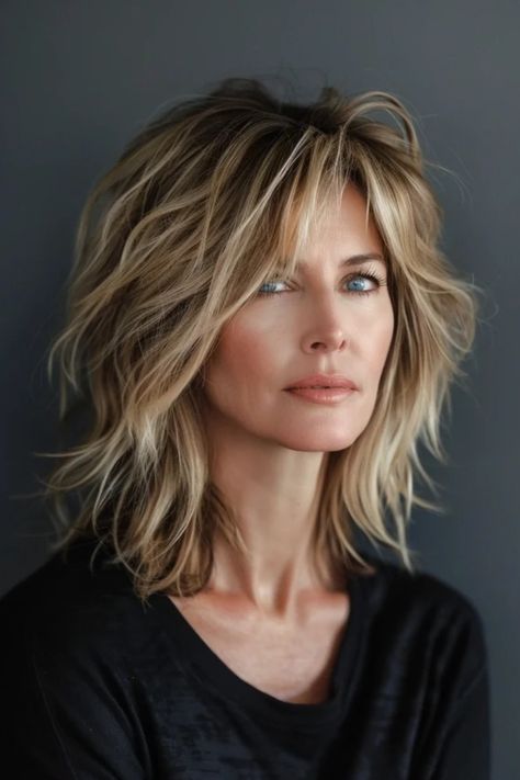 A woman with tousled short blonde hair and blue eyes, gazing to the side, against a grey background. Long Bob With Choppy Layers, Shag Hairstyles Low Maintenance, Shaggy Bangs Fine Hair, Choppy Layered Bob Hairstyles Medium, Edgy Textured Haircuts, Shaggy Layered Haircuts Medium Fine Hair, Shag No Bangs Hairstyles Medium, Choppy Lob Fine Hair, Hair Styles Shoulder Length With Bangs