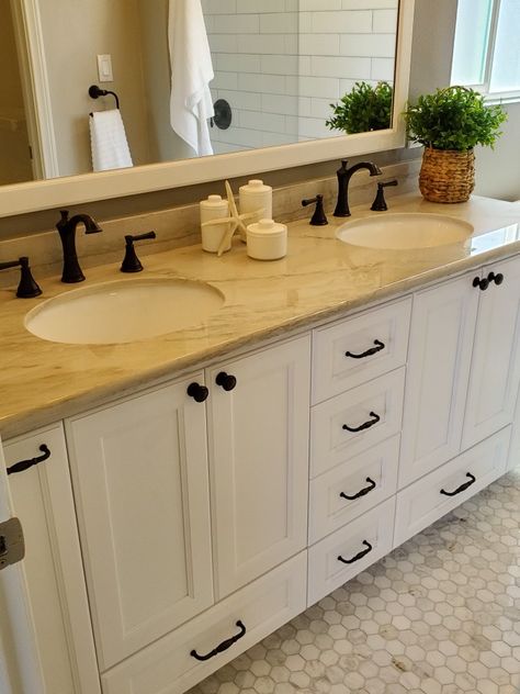 This master bath has exquisite attention to detail. Hexagon carerra floor tile, dual sinks. Edison bulbs are casting a yellow hue. Shower has large subway style tile that continues outside of shower to bathroom wall Yellow Bathroom Countertop, Bathroom Yellow Countertop, Tan Countertops Bathroom, Marble Countertops Bathroom, Cream Bathroom, Subway Style, Yellow Marble, Edison Bulbs, Carrera Marble