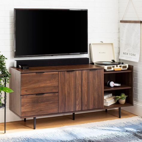 This modern asymmetrical TV stand offers a wide variety of both open and closed storage with multiple cubbies on the right, 2-deep drawers on the left, and 2-doors that open up to additional shelving with cord management options so you can easily tuck away DVDs, gaming devices, or toys. 58 in. wide, this media console features a cutout tray-style section where you can put a record player, your favorite house plant or use it as a bar counter. This entertainment stand accommodates TVs up to 46 in. Walnut Tv Stand, Tv Stand Console, Flat Panel Tv, Tv Stand Wood, Modern Tv Stand, Modern Tv, Modern Storage, Wall Mounted Tv, Furniture Deals