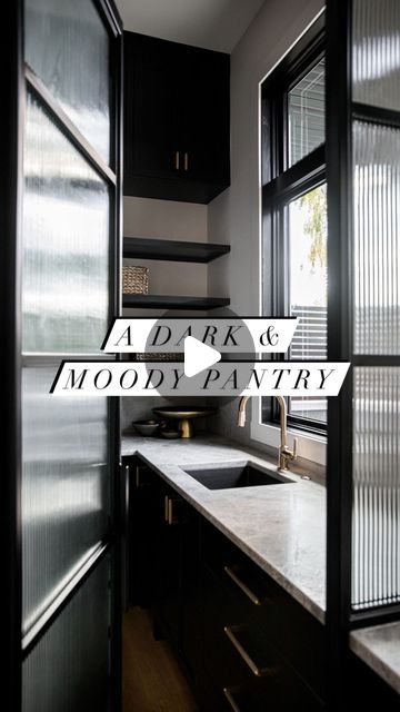 Melissa Manzardo Hryszko on Instagram: "Since this pantry has a large window overlooking the backyard, we knew we could be bold with the cabinetry and extend the black cabinets into this area of the home.  The custom iron & receded glass door is a partition between the kitchen and this large and well-organised pantry.  A combination of open shelving, concealed cabinetry, and an extensive amount of counter space makes this a dream pantry area we would happily have in our own home!   #pantry #pantryorganization #homeorganization #pantrydesign #kitchendesign #blackcabinets #instahome #housegoals" Contemporary Pantry Door, Black Walk In Pantry, Black Pantry Cabinets, Black Pantry Shelves, Black Glass Pantry Door, Pantry Doors With Fluted Glass, Black And Glass Pantry Door, Black Steel Framed Pantry Doors, Black And White Pantry