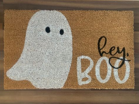 "Bring a friendly Halloween greeting to guests and trick-or-treaters with this \"hey, boo\" welcome mat.  Doormats are hand-painted with outdoor-rated paint. These natural coir doormats measure approximately 18\"x30\" in size and have non-slip backing. This mat is suitable for outdoor use but keeping it out of rain and direct sunlight will prolong the life of the design. Avoid saturating with water. Shake or sweep to clean. Listing includes one coir doormat only. Listing photos include display o Doormat Display Ideas, Diy Halloween Outdoor Mat, Welcome Mat Halloween, Ghost Welcome Mat, Halloween Mat Painting Ideas, Cute Halloween Doormat, Halloween Coir Doormat, Door Mat Painting Diy Halloween, Diy Ghost Doormat