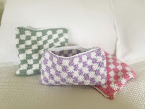 "These checkered crochet pouches are perfect for toiletries, makeup, & all your cosmetic needs. They can also be used as pencil cases, a travel essential, and much more!  These pouches are 9\" in length and come in widths of either 7\" and 5 1/2.\" All zippers are white nylon and sewn with white thread." Checkered Pouch Crochet, Crochet Makeup Bag, Crochet Pouches, Checkered Crochet, Pencil Case Pattern, Crochet Pencil Case, Cute Pencil Pouches, Crochet Travel, Crochet Purple