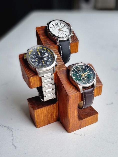 Wooden watch display stand. Elegant way to exhibit your watches. Handmade out of solid wood and stained to create rustic finish. Perfect gift idea for a watch enthusiast who likes to put their prized possessions on show.  Top part is designed to rest the watch case on the angle in a very presentable position. This is also very functional for the solar powered watches that should not be stored away.  Stand is crafted from solid pieces of timber therefore natural imperfections like knots may be featured on the surface. These, if present will be purposely preserved and stained just like the rest of the stand to enhance the innate character of the product as well as achieve the rustic style. Two types of stands are available as standard: featuring two or three spaces (stand for more that three Watch Stand Design, Timber Jewellery Stand, Wooden Watch Holder, Wooden Small Projects, Wooden Watch Stand, Diy Watch Display, Watch Stand Diy, Wooden Key Holder Ideas, Diy Watch Holder