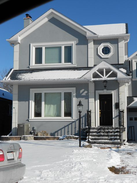 This one's my favourite.  I love the grey stucco, the black roof and door, the white embossments and trim.  And I really like the little octagonal window.      Add a porch and this one's the winner! Light Grey And White House Exterior, Gray And White Exterior House Colors, Light Grey House Exterior White Trim, Gray And White House Exterior, Light Grey Exterior House Colors, Grey Stucco House Exterior, Octagonal Window, Grey House White Trim, Grey Stucco