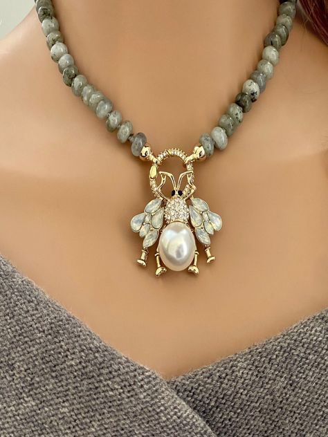 This is a beautiful hand-knotted Labradorite Rondelle semi-precious stone necklace. The round Micro Pave connector clasp is easy to open and the bee pendant is removable. Wear the necklace with or without the pendant. A true statement piece. The length of the necklace including the clasp is approximately 16.5ins. The Cubic Zirconia and Pearl Bee Pendant is a unique piece of jewe...#Exploring #Beauty #Exploring #the #of #Treasures #Unveiling #Natures #Gemstone #Jewelry #World #of #Allure #the Semiprecious Stone Jewelry Necklace, Diy Semi Precious Stone Jewelry, Bee Pendant Necklace, Handmade Jewelry Ideas Necklace, Unique Pearl Jewelry, Unique Pearl Necklace, Semi Precious Stone Jewelry, Stone Jewelry Necklace, Semi Precious Necklace