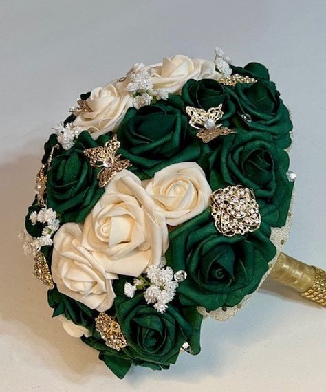 This beautiful 11 inch Emerald / Hunter's Green bouquet has Ivory / Champagne real touch roses and some babies breath. Scattered throughout are gold crystal brooches and butterflies. The handle is trimmed in gold diamond wrap. Real touch roses are a perfect choice for Quinceanera and Wedding because the blooms will look fresh the whole day. If they appear to be a little crushed in transit, just place in a heavy glass or vase (no water, please!) and they will get back to their original shape in no time. Bouquets are mailed using USPS Ground Advantage which takes approximately 2-5 business days for delivery. If you need your bouquet sooner, please let us know and we will ship via USPS Priority Mail - the difference will be given to you at time of receiving your bouquet order.  Thank you for Bouquet Emerald Green, Quince Bouquet, Emerald Green Quinceanera Theme, Green Quinceanera Theme, Gold Wedding Bouquets, Quinceanera Bouquet, Gold Wedding Flowers, Bouquet Green, Extravagant Wedding Dresses