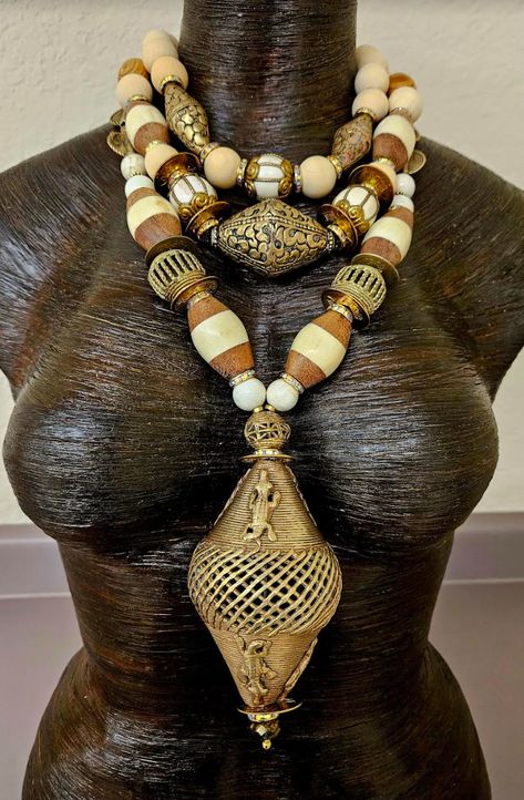 Three strands of exotic, wild and rare beads adorn this tribal - ethnic inspired Tibetan, Asian and African oversized beaded chest piece, which either men or women can wear. A very large (4" x 2.5") hand crafted African lost wax brass crocodile bead is the pendant on this bold piece. The other components include magnesite, Chinese vintage brass coins, gold aurora borealis rhinestone rondelles, African bone and wood bicone beads, more lost wax brass cagework beads, Tibetan brass repousse, brass cagework conch beads, round blonde wood beads, beige wood barrel beads, African brass sundials and small bone rondelles. Despite it's size, this is a fairly lightweight piece with only the pendant bead having any real weight. Adjusts from 17-20". Gold tone hardware, a lobster claw clasp and a 3" exte Gaudy Jewelry, Rocker Chic Accessories, Rare Beads, Unique Pendant Necklace, Long Statement Necklace, African Decor, Chest Piece, Mermaid Necklace, Couture Jewelry