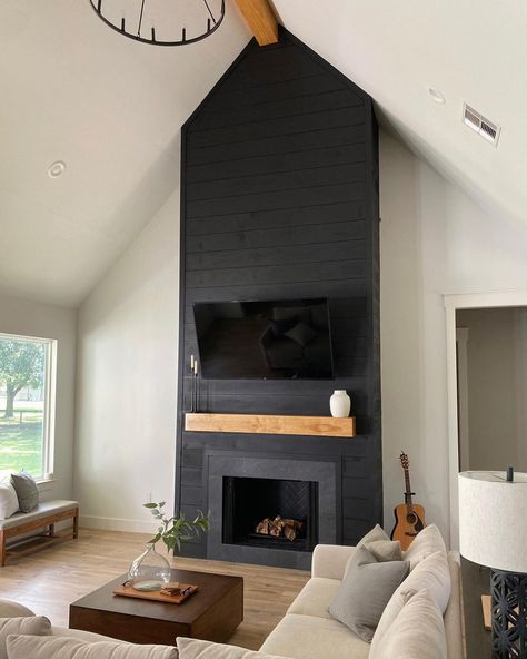 Black floor to ceiling shiplap fireplace is finished with a light wood mantel and flat panel TV. A square stained wood coffee table in front of the fireplace is framed by a beige sectional couch. Black Fireplace Wall, Black Brick Fireplace, Black Shiplap, Design Camino, Cottage Fireplace, Black And White Living Room, Black Fireplace, White Shiplap Wall, Shiplap Fireplace