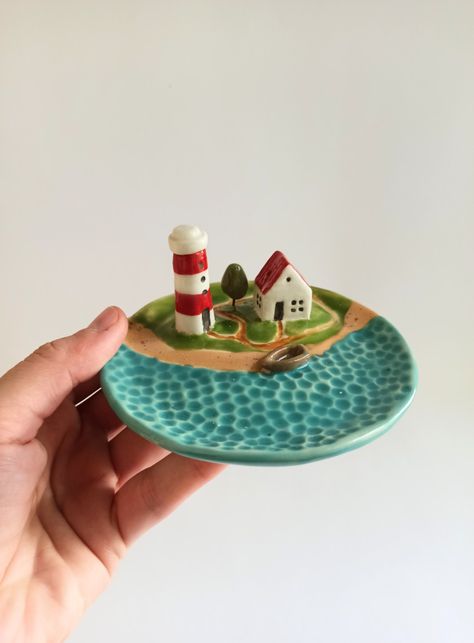 This is a small ceramic dish with a cute lighthouse and house. This is a universal dish for storing jewelry, and it is also a holder for incense sticks. Home Clay Projects, Small Ceramic Dish, Clay Art Jewelry Holder, Fun Ceramics Ideas, Creative Ceramic Projects, Air Dry Trinket Dish, Clay Jewelry Holders, Clay Projects Ideas Ceramic Art, Diy Clay Jewelry Holder