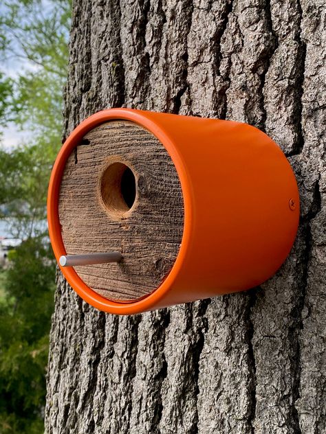 This orange handcrafted birdhouse features a deeper depth, durable vinyl tube with surface and edges sanded smooth and 4 coats of orange paint applied. Adding a one-of-a-kind kind, upcycled rustic charm, each end features circular cut reclaimed historic Michigan barnwood. A sleek aluminum rod allows birds to perch at entry. Moisture relieving holes are at the bottom. The house mounts to a wall or tree by a shou sugi ban wood burn treated back plate with included stainless-steel screw. Once the plate is mounted to the wall, the house slides over the back plate and is secured at each side with color-matched, painted screws. This allows for simple seasonal removal and cleaning as well. Specs: Tube = 4-3/4" deep x 5" diameter vinyl End Caps = 4-1/2" wood Entry = 1-1/2" hole with sanded edges B Sugi Ban Wood, Mcm Minimalist, Wood Bird House, Modern Birdhouses, Homemade Bird Houses, Bird Houses Ideas Diy, Handmade Birdhouses, Bird House Feeder, Unique Bird Houses