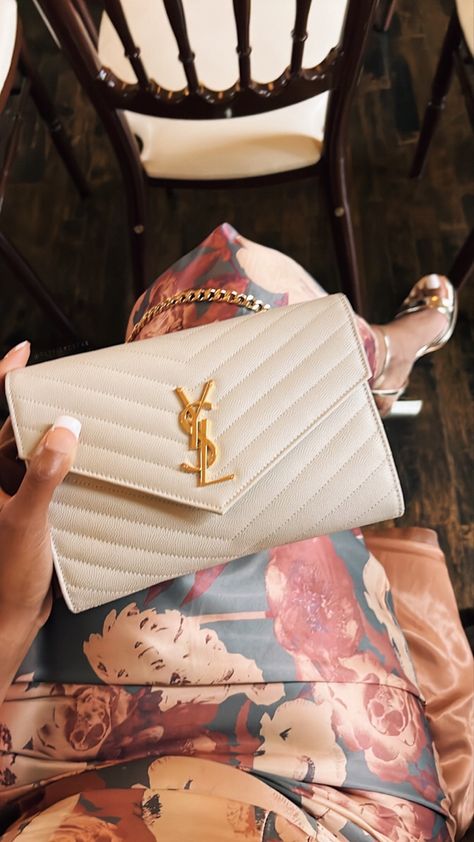 Black woman sitting and holding a cream ysl bag Ysl Clutch Bag Outfit, Clutch Bag Wedding Guest, Clutch For Wedding Guest, Ysl Clutch Outfit, Ysl Wallet On Chain Outfit, Wallet On Chain Outfit, Wedding Guest Clutch, Black Woman Luxury Aesthetic, Ysl Wallet On Chain