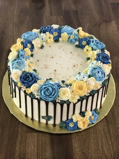 Floral Buttercream Cake. 2 x 10 inch layers using chocolate sponges. Chocolate custard filling. Buttercream coating with a dark chocolate drip. Various shades of dark blue, light blue, yellow and cream flowers. Finished off with white and gold sugar crystals and pearls. 10 Inch Cake Designs, Blue And Yellow Graduation Cake, Blue Floral Cake Birthday, Yellow And Blue Cupcakes, Blue And Yellow Birthday Cake, Blue And White Cake Design, Dark Blue Cake, Blue And Yellow Cake, Wedding Cake Designs Blue