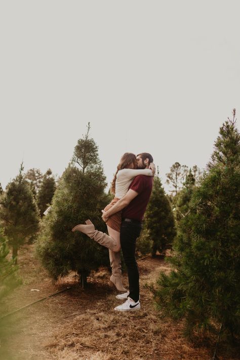 Christmas Tree Farm Mini Session Couple, Couple Poses In Front Of Christmas Tree, Christmas Tree Photoshoot Couple, Couples Tree Farm Photoshoot, Couple Christmas Tree Photos, Christmas Tree Farm Photo Shoot Props, Pine Tree Photoshoot, Christmas Tree Farm Engagement Pictures, Family Christmas Pictures Outdoor