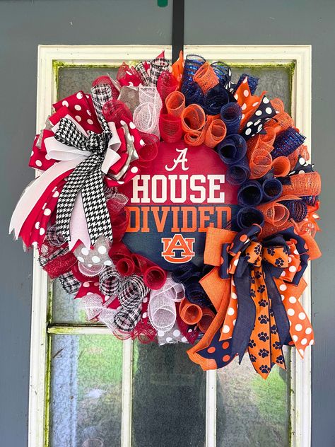 Showcase your spirited household rivalry with this unique "House Divided" wreath! This handcrafted wreath perfectly blends the crimson and white colors of the University of Alabama and orange and navy blue of the Auburn Tigers.  This beautiful, handcrafted wreath is made with high quality deco mesh and wired ribbon, and a hand painted centerpiece sign. The sign was painted with acrylic paint and lettering was made with vinyl; it is coated in multiple layers of mod podge to prevent the paint from Sports Team Wreaths, House Divided Football Wreath, House Divided Football Sign, Alabama Football Wreath, House Divided Football, Alabama Crafts, House Divided Wreath, Alabama Wreaths, Sports Crafts