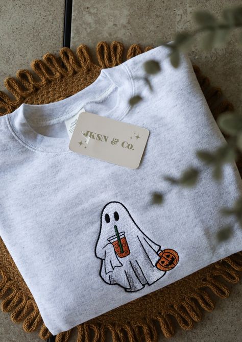 Get ready for the spooky season with our Embroidered Iced Coffee Ghost Crewneck! This cute and cozy sweatshirt features an adorable ghost enjoying an iced coffee, perfect for Halloween and fall fashion lovers. Why You'll Love It: Unique Design: Custom embroidered ghost with iced coffee, exclusively designed for this crewneck!  High-Quality Material: Made from soft, durable fabric to keep you comfortable all autumn long!  Perfect for Fall: Ideal for Halloween parties, pumpkin patch visits, or jus Fall Sweater Designs, Cute Halloween Crewneck, Halloween Embroidery Designs Sweater, Halloween Clothes Aesthetic, Fall Embroidered Sweatshirts, Cricut Sweaters, Embroidered Clothes Ideas, Sweatshirts Ideas, Autumn Sweatshirts