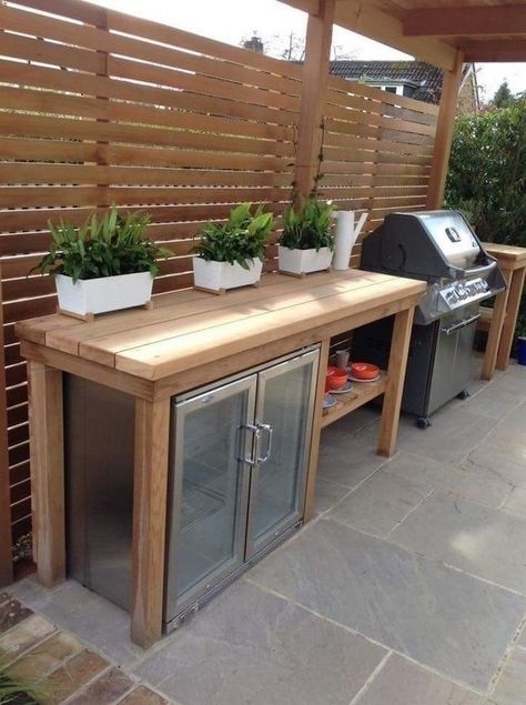 outdoor kitchen ideas wooden table with fridge and barbecue grill three potted plants on top stone tiles on the floor Wooden Kitchen Island, Small Outdoor Kitchen, Small Outdoor Kitchens, Outdoor Bbq Area, Drink Cooler, Outdoor Kitchen Plans, Outdoor Bbq Kitchen, Outdoor Kitchen Design Layout, Backyard Kitchen