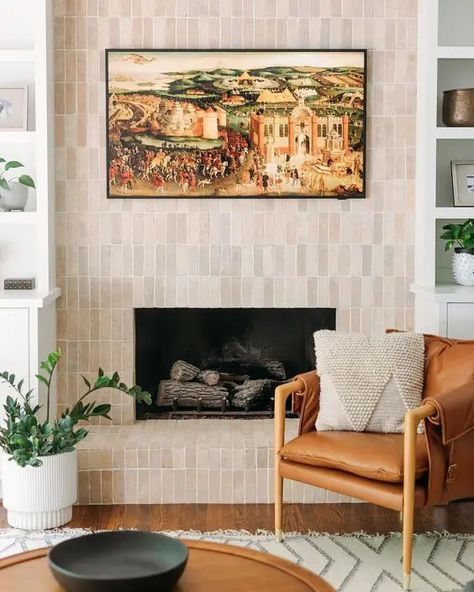 a fireplace clad with neutral skinny tiles is a stylish solution for a modern or mid century modern space Black Terracotta Tile Fireplace, Fireplace Zellige Tile, Tile Wall In Living Room, Natural Tile Fireplace, Spanish Tile Fireplace Ideas, Zellige Fireplace Surround, Tiled Living Room Wall, Zellige Tile Fireplace Surround, Modern Tile Fireplace Ideas