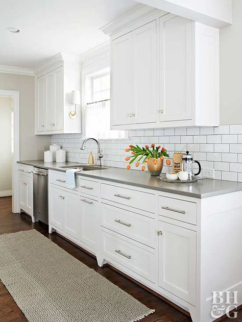 Preserving the galley-style kitchen layout eliminated the need to move plumbing or electric wiring—a budget-saver that allowed for new hardwood floors, cabinets, finishes, and appliances. A subway tile backsplash reflects light throughout and creates clean lines with newly painted cabinets. Stainless-steel appliances and drawer pulls keep the kitchen contemporary and ready for cooking. Cape Cod House Interior, White Galley Kitchen, Small White Kitchens, Gray Counter, Galley Kitchen Design, Galley Kitchen Remodel, Galley Style Kitchen, Diy Kitchen Renovation, House Makeover