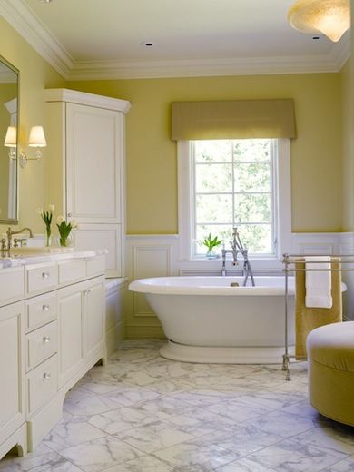 The peaceful quality of pale straw combined with white is undeniable. Elegant details in this serene setting include thick ceiling molding, glass knobs on the vanity, and a corner cabinet. The valance, upholstered ottoman, and bath towel carry the straw color around the room. Yellow Bathroom Walls, Yellow Bathroom Decor, Yellow Paint Colors, Gray Bathroom Decor, Yellow Bathroom, Bathroom Color Schemes, Lemon Sorbet, Living Room Small, Bathroom Paint Colors