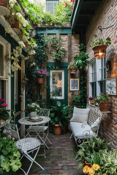 Cozy courtyard with white garden furniture, surrounded by plants and brick walls. Small Cottage House Interior, Small Patio Decorating Ideas Plants, Flower Patio Ideas, Small Balcony With Plants, Mini Patio Ideas Small Spaces, Cute Patio Ideas Small Balconies, Small Outdoor Deck Decorating, Long Narrow Patio Ideas, Tiny Porch Ideas