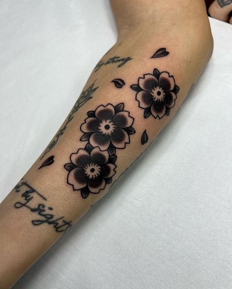 16 Beautiful Cherry Blossom Tattoo Ideas For Women To Express Blooming Love Traditional Cherry Blossom Tattoo Black, Traditional Cherry Blossom Tattoo Design, Cherry Blossom Finger Tattoo, Cherry Blossom Tattoo Black And White, Black Cherry Blossom Tattoo, Japanese Sakura Tattoo, Traditional Cherry Blossom Tattoo, Japanese Blossom Tattoo, Flower Tattoos Black